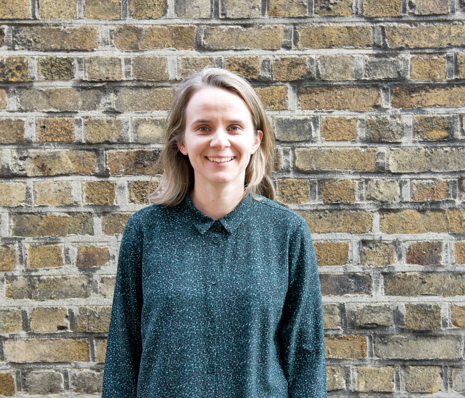 Headshot of Claire Tadla, Irish Refugee Council Information and Referral Services Coordinator in front of a brick wall 